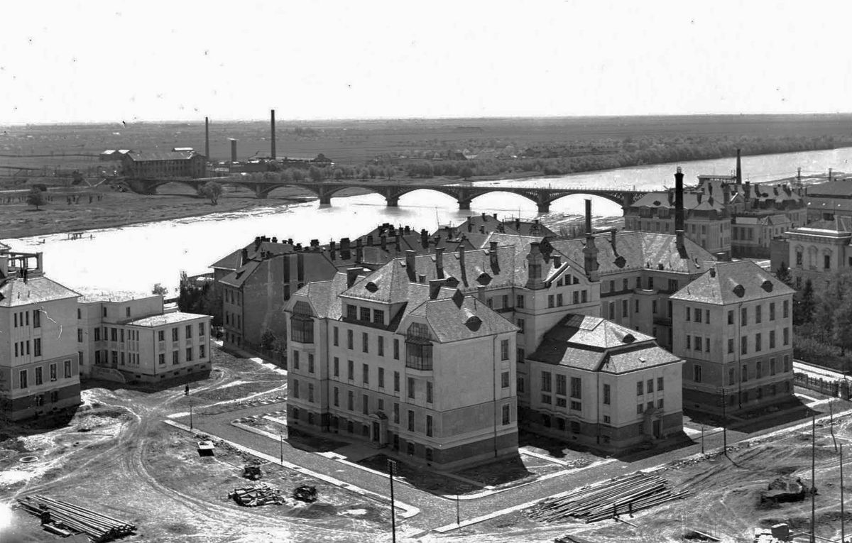 A Szeged-Temesvár vasútvonal egyik legfontosabb eleme a szegedi vasúti híd. A szegedi klinkakert 1929-ben, háttérben a vasúti híd és az újszegedi kendergyár látható. fotó: Fortepan / Kozma János