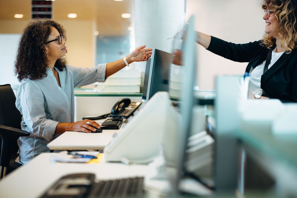 Woman,Standing,At,Reception,Desk,Giving,Her,Card,To,The